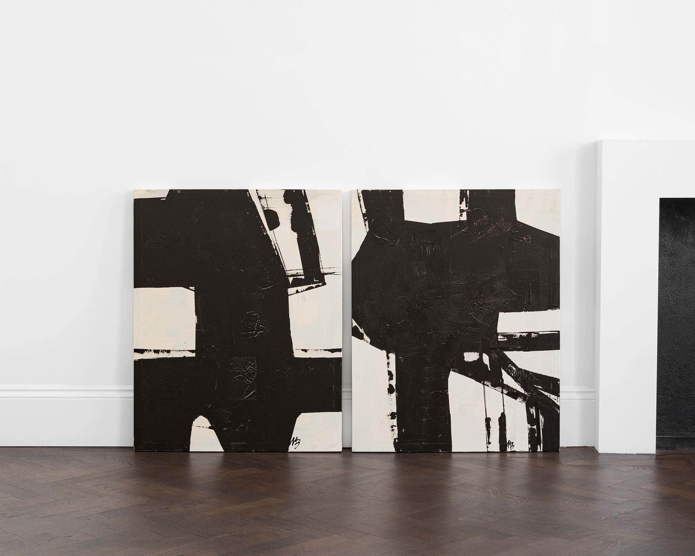 A pair of bold graphical black paintings on a white background.